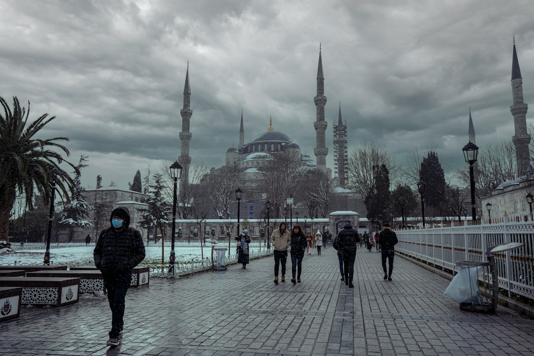 People walk past a mosque on a cloudy day