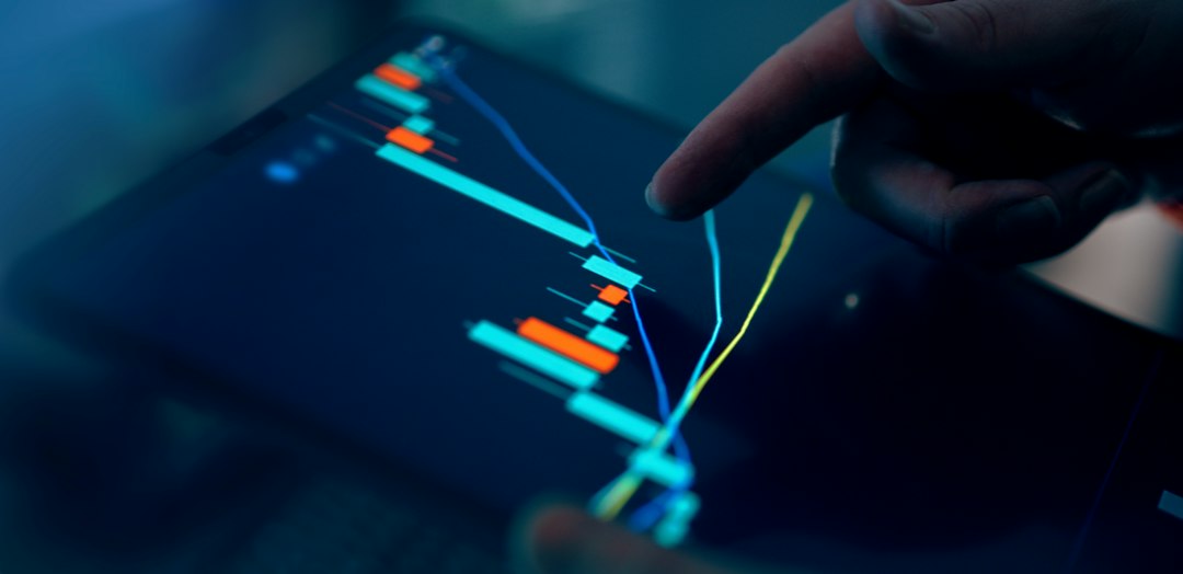 Fingers interacting with a stock market graph on a tablet