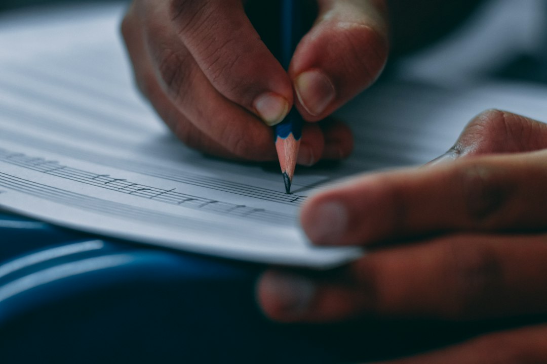 a person writing on a piece of paper with a pencil