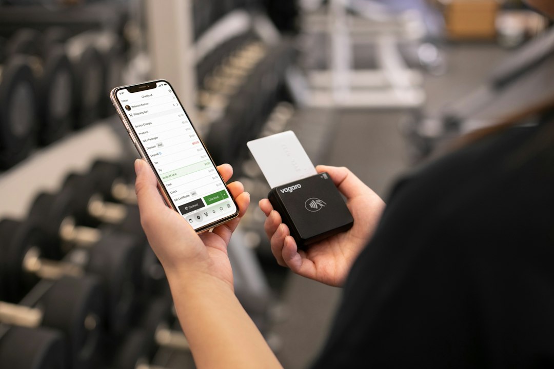 Person holding phone and payment device in gym