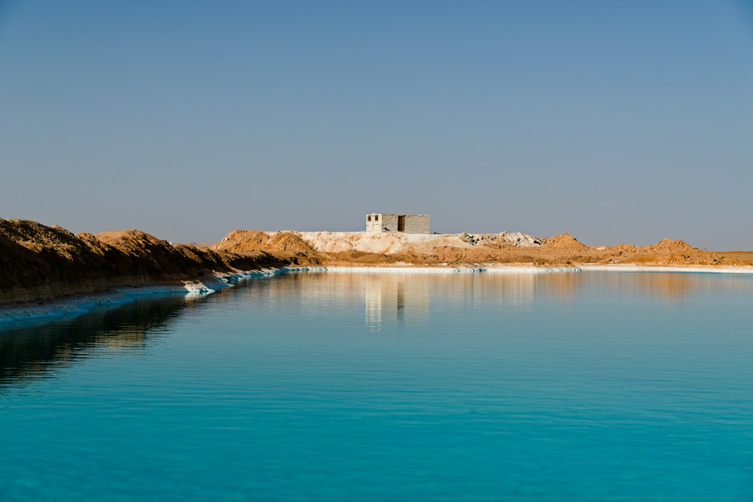 Bright blue water with distant buildings and desert landscape.