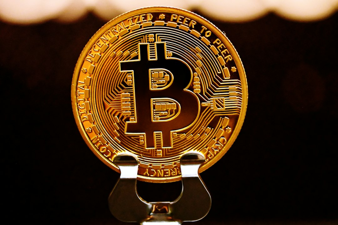 a golden bit coin sitting on top of a metal stand